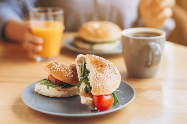 Büyük ve ağız sulandıran bir sandviç. Kahve masasının üzerinde sulu bir dolma var. Hazır kafede iki kişilik kahvaltı.