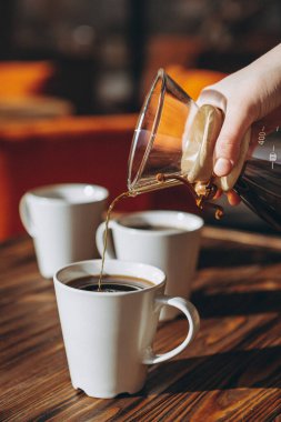 Sehpada serbest çalışan insanlar kahve içer, sohbet eder, bilgisayarda çalışır ve telefon kullanır.