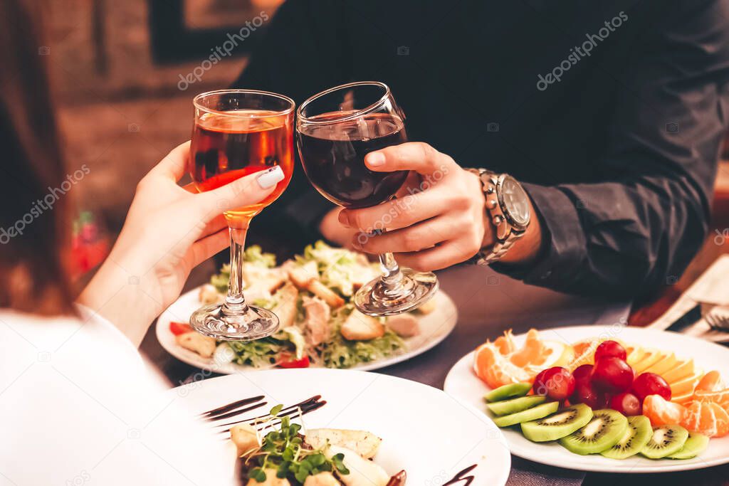Man and women drink red and white wine.  lose-up of hands with glasses. They celebrate the new year.