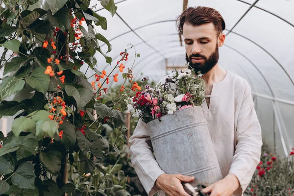 Mutlu sakallı erkek çocuk bakıcısı seradaki bitkileri buduyor.