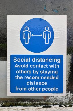 Önerilen mesafeyi koruyarak başkalarıyla temas kurmaktan kaçının diyen sosyal uzaklık işareti