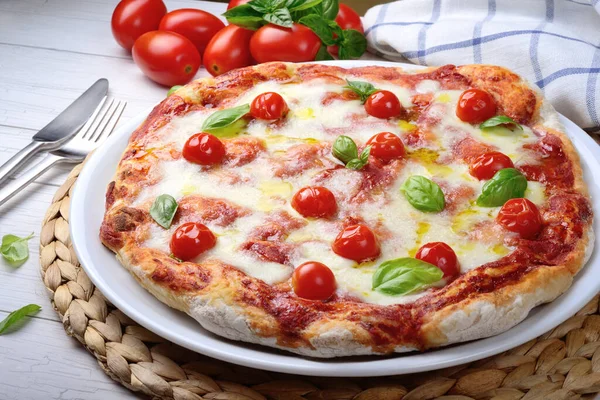 Mozzarella 'lı pizza, beyaz ahşap arka planda kirazlı domates ve fesleğen..