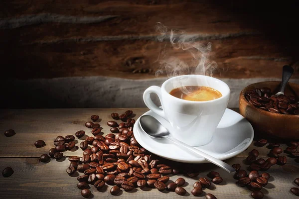 Espresso kahve ve kahve çekirdekleri, eski ahşap masada buharda pişmiş espresso bardağı..