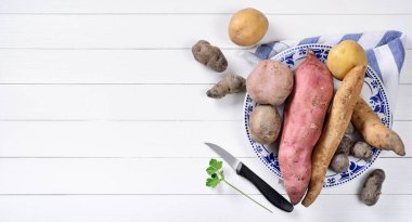 Beyaz ahşap masa üzerinde beş çeşit patates, üst görünüm, metin için yer.