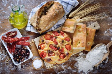 Vişneli domates ve zeytinli Focaccia Barese, zeytin ekmeği, beyaz Focaccia, kuru domates ve ahşap zemin üzerinde zeytin, üst görünüm.