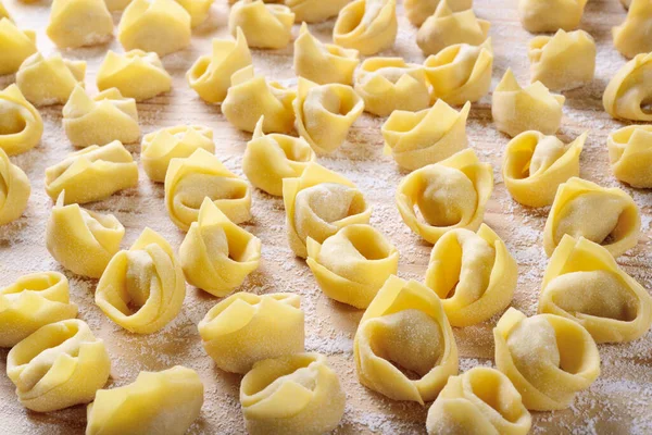 Ev yapımı tortellini. Un kaplı pasta tahtasında yumurtalı makarna. İtalyan dolgulu taze makarna, tipik Emilian şehirleri Bologna ve Modena..