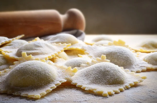 Homemade spinach and ricotta ravioli on pastry board, closeup.