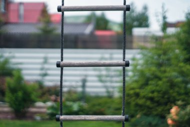 Yeşil çimen ve bitkilerden oluşan bir arka planda ip merdiveni