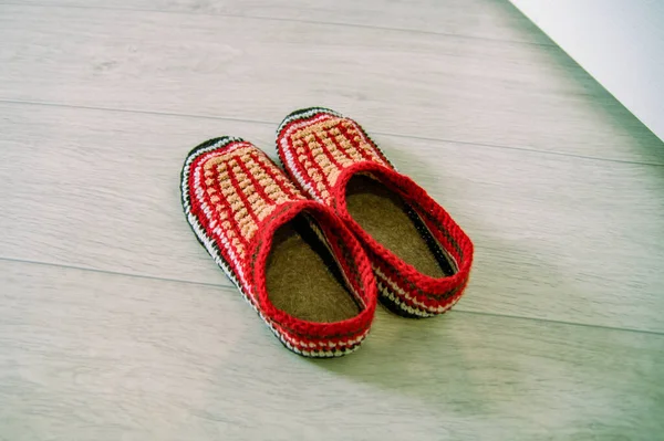 Red knitted wool slippers close-up stand on the floor