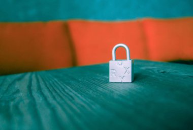 Tahta bir masada harflerle küçük metal asma kilit.