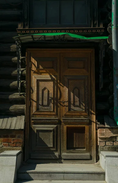 石畳で舗装された通り 弧を描く古い木製のドア ライトブラウンのファサード クリーパー植物に囲まれたドア — ストック写真
