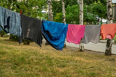 Mavi gökyüzünün önündeki çamaşır ipinde bir grup birincil renkli tişört.