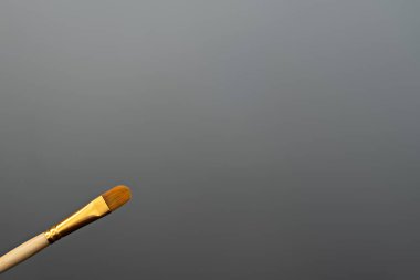 Boyalarla resim yapmak için sanatsal fırçalar. Gri arkaplanda mesaj için yer var. Fırçanın ahşap bir tabanı, sentetik kılları var..