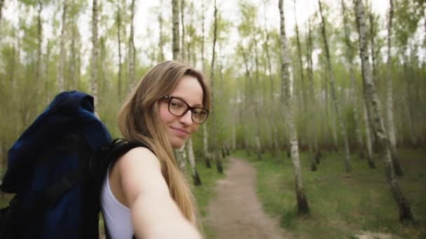 Retrato de uma jovem mulher feliz segurando a mão de seu namorado enquanto caminha na trilha da floresta. Casal desfrutando de uma caminhada na natureza — Vídeo de Stock