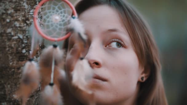 Retrato de mujer caucásica con ojos verdes posando en el bosque cerca de corteza de árbol con atrapasueños en forma de ojos — Vídeo de stock