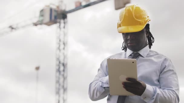 Retrato de um homem africano com chapéu duro usando tablet no canteiro de obras — Vídeo de Stock