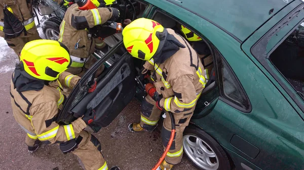 Equipe de bombeiros tentando cortar a porta do carro aberto para salvar a pessoa envolvida no acidente — Fotografia de Stock