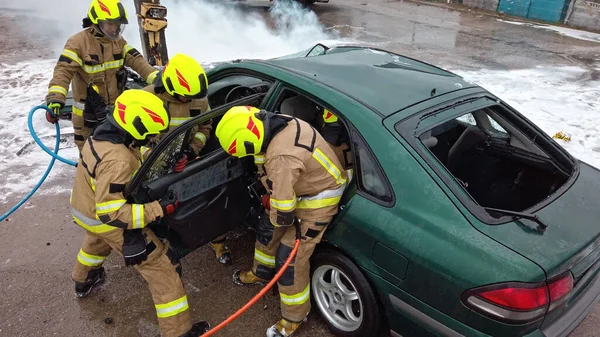 Equipe de bombeiros tentando cortar a porta do carro aberto para salvar a pessoa envolvida no acidente — Fotografia de Stock