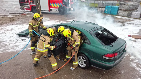 Equipo de bomberos tratando de abrir la puerta del coche para salvar a la persona involucrada en el accidente —  Fotos de Stock