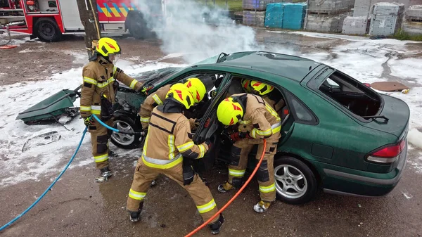 Equipo de bomberos tratando de abrir la puerta del coche para salvar a la persona involucrada en el accidente —  Fotos de Stock