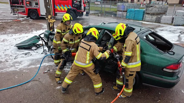 Equipo de bomberos tratando de abrir la puerta del coche para salvar a la persona involucrada en el accidente —  Fotos de Stock