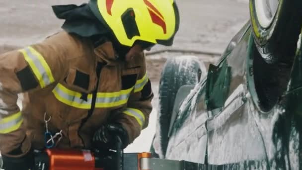 Bombeiro tentando abrir a porta do carro para salvar a pessoa envolvida no acidente. Movimento lento — Vídeo de Stock