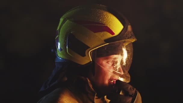 Potret seorang petugas pemadam kebakaran yang sedang beraksi berbicara tentang walkie talkie. Pantulan tembakan pada helm. Gerakan lambat — Stok Video