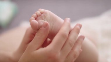 Anne masaj yapıyor ve küçük bebek ayaklarını gıdıklıyor. Ağır çekim çekimini kapat