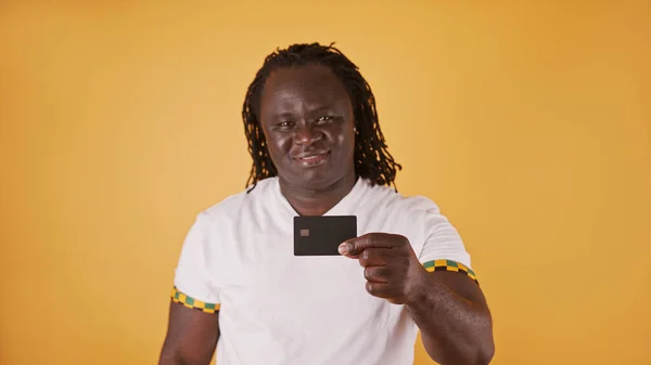 幸せなアフリカ人男性でホワイトショークレジットカードでカメラ以上オレンジ背景 — ストック写真