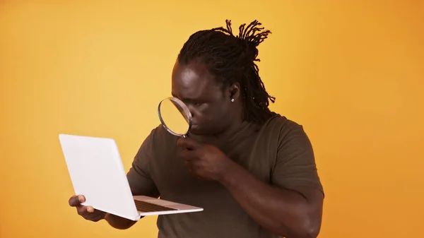 Close-up tiro de um homem africano usando lupa para ler a partir da tela do laptop — Fotografia de Stock