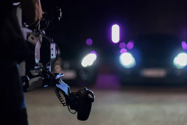Cameraman with professional movie camera recording night street racing sport cars — Stock Photo, Image