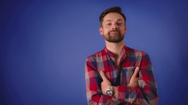 Knappe blanke man met gekruiste armen glimlachend geïsoleerd op de blauwe achtergrond — Stockvideo