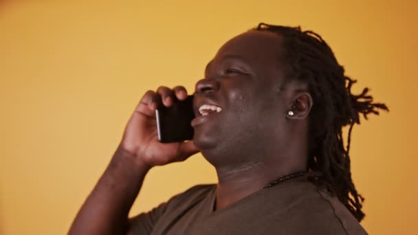 Portret Afrykanina rozmawiającego przez telefon. Izolacja na pomarańczowym tle — Wideo stockowe