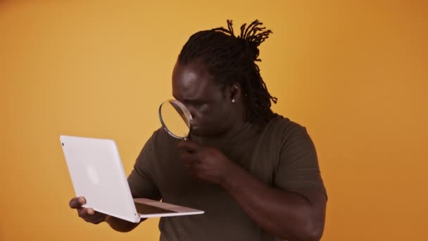 Close-up tiro de um homem africano usando lupa para ler a partir da tela do laptop — Vídeo de Stock