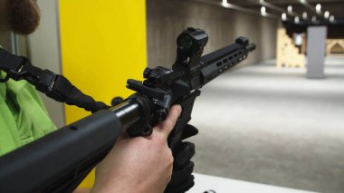 Yetişkinler atış poligonunda bir saldırı tüfeği yüklüyor..