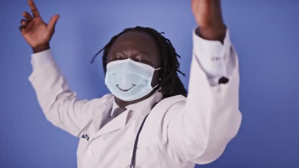 Dansande glad glad glad afrikansk doktor i ansiktsmask med leende ritning — Stockvideo