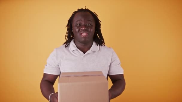 Έννοια παράδοσης: Αφρικανικός άνθρωπος παράδοσης - courier παραδίδοντας το κιβώτιο συσκευασίας - αντιγράψτε το διάστημα απομονωμένο — Αρχείο Βίντεο