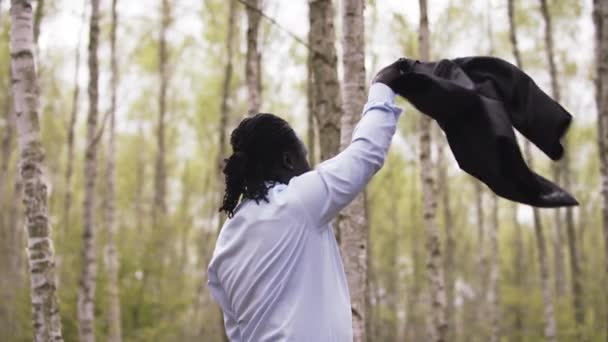 Hombre de negocios africano celebrando el éxito en la naturaleza mientras hace girar su traje — Vídeo de stock