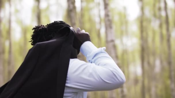 Uomo d'affari africano di successo mettendo il suo vestito sopra le spalle nel parco — Video Stock