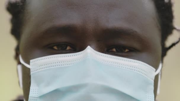 Zblízka záběr afrického muže s lékařskou maskou přes tvář v parku — Stock video