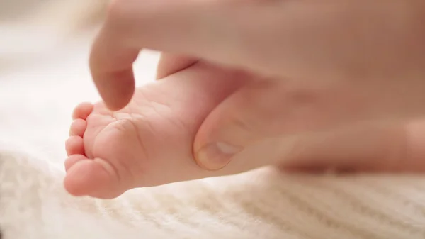 Anne masaj yapıyor ve küçük bebek ayaklarını gıdıklıyor. Ağır çekim çekimini kapat — Stok fotoğraf