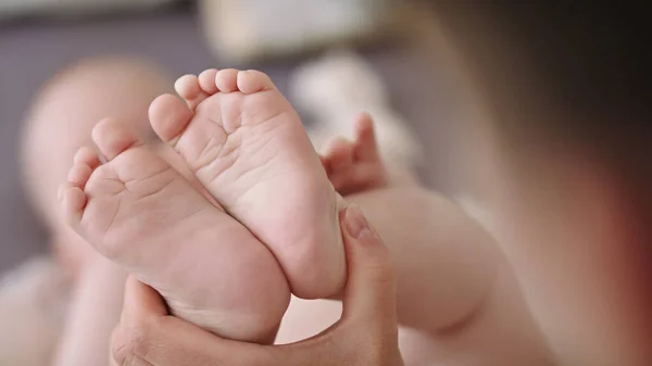 Mor masserar och kittlar små babyfötter. närbild slow motion skott — Stockfoto