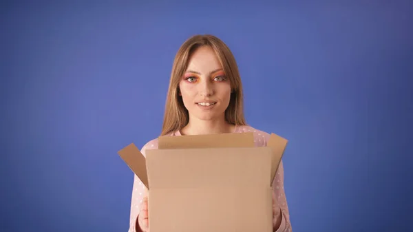Junge kaukasische Frau mit gepackten Pappkartons und überraschtem Gesicht isoliert auf blauem Hintergrund. Kopierraum — Stockfoto