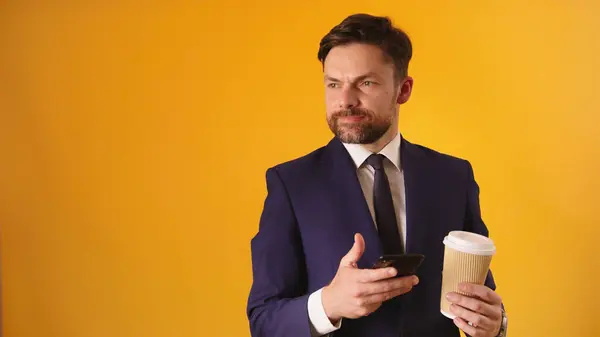 Attractive Caucasian Businessman with Cellphone and Coffe - Isolated on Yellow background — Stock Photo, Image