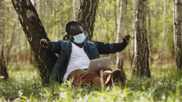 Nowa normalność. Koncepcja zdalnej pracy. Afrykański człowiek za pomocą laptopa w przyrodzie i rozciąganie — Wideo stockowe