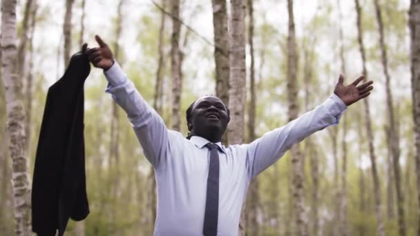 Эмоциональный успешный африканский бизнесмен поднимает руки вверх и крутит свой костюм — стоковое видео