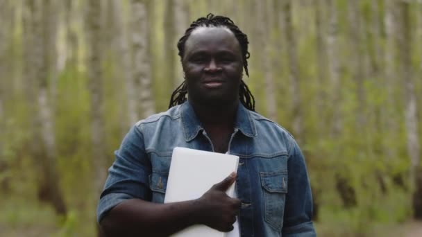 Portret van een jonge Afrikaanse man met tablet in het park — Stockvideo