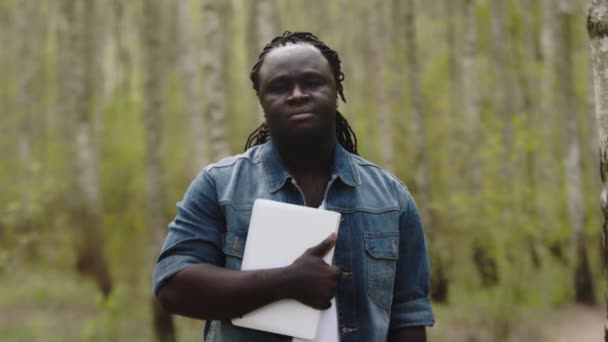 Portret van een jonge Afrikaanse man met tablet in het park — Stockvideo