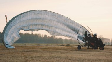 Paramotorgliding. Başarılı bir iniş, planör paraşütçüyü çözüyor.