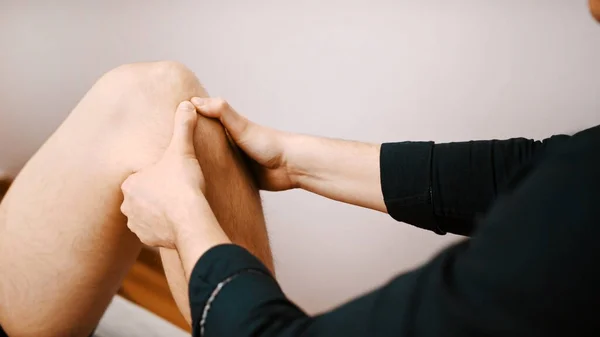 Jovem com o joelho examinado por especialista. Fisioterapia flexibilidade do joelho — Fotografia de Stock